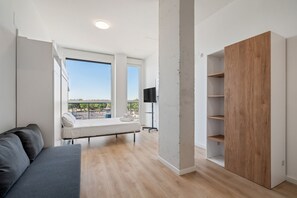 Une chambre moderne avec un lit, un canapé gris, une armoire en bois et un meuble pour la télévision.