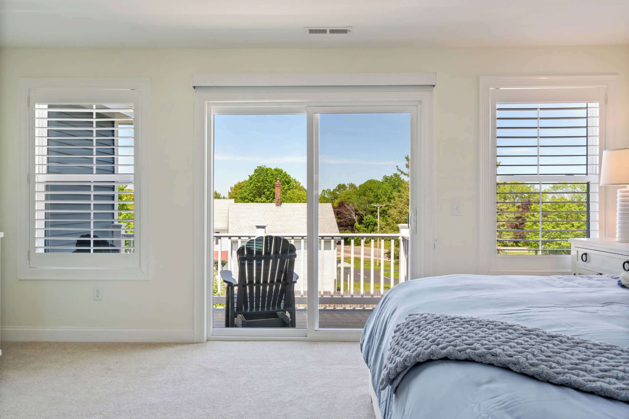 A bedroom with a bed, a chair, and a sliding glass door leading to a balcony.