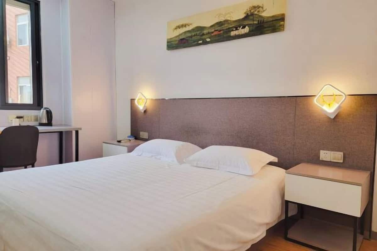 A neatly arranged hotel room with a large bed, bedside tables, a desk, and a chair.