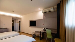 Habitación de hotel con dos camas, un escritorio, una silla y un aire acondicionado.