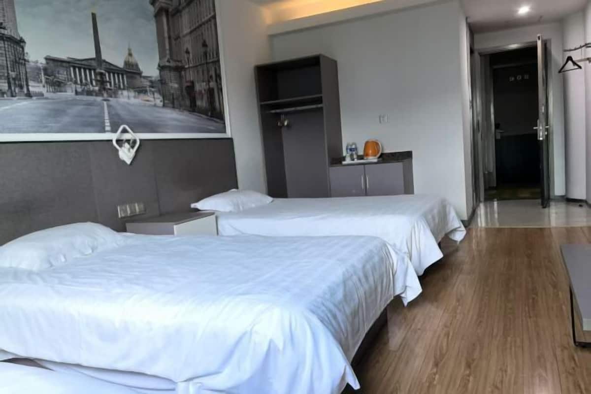 A hotel room with two beds, a wardrobe, a painting on the wall, and a door leading to another room.