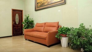 A lobby with a leather sofa, a wooden door, and several potted plants. - Fuman Hostel (Shanghai)