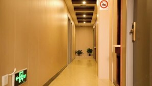 A hotel corridor with a no-smoking sign, an emergency exit sign, and a potted plant. - Fuman Hostel (Shanghai)