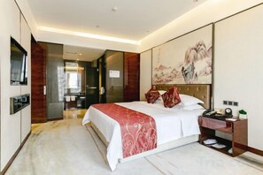 A modern hotel room with a large bed, a bedside table, a flat-screen TV, and a painting on the wall. - Tongren Jinjiang Hotel (Tongren)