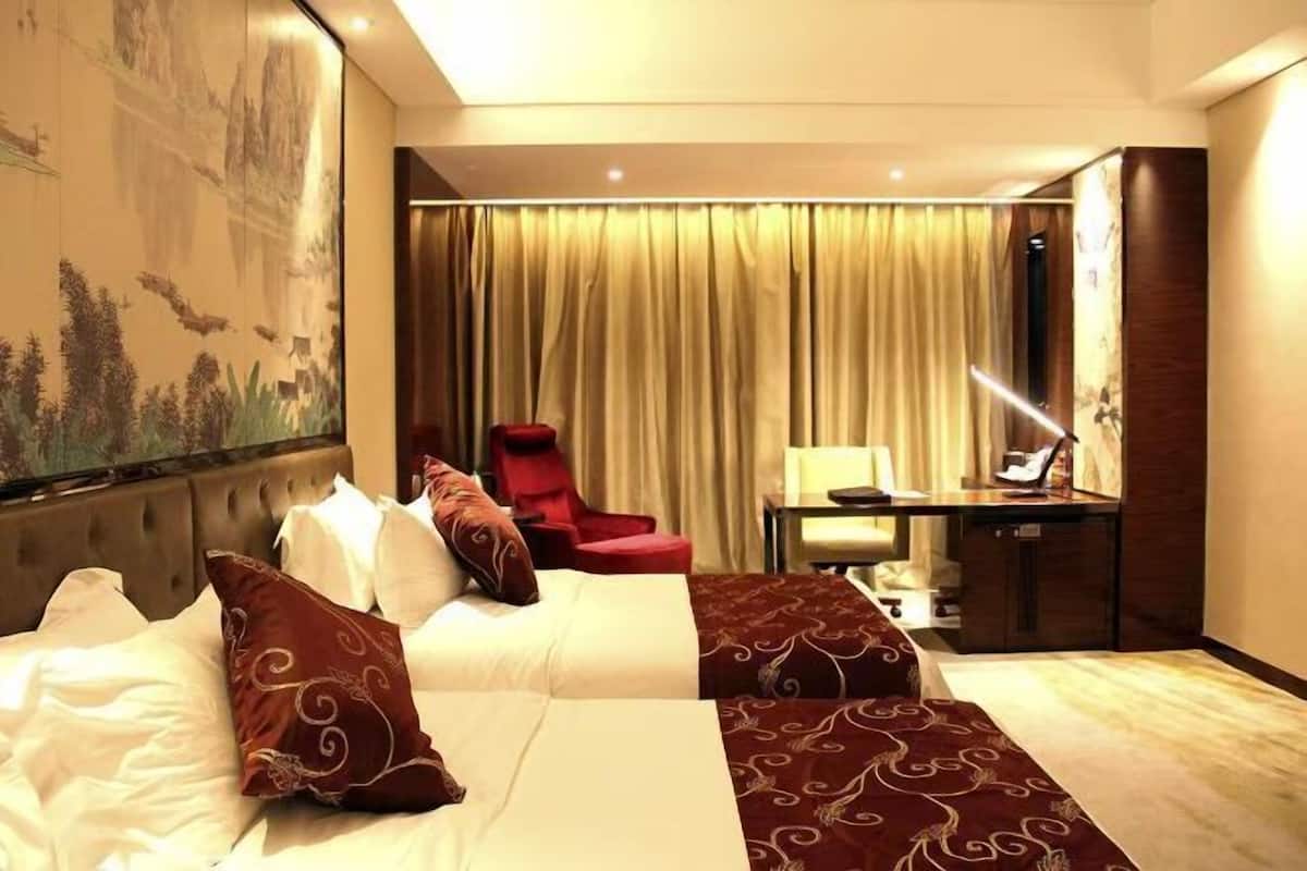 Una habitación de hotel con una cama grande, un escritorio, una silla y una cortina.
