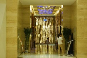 Un vestíbulo de hotel con piso reflectante, una pared decorativa y una lámpara en el techo.