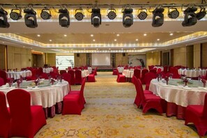 A banquet hall with round tables, red chairs, and a carpeted floor. - Tongren Jinjiang Hotel (Tongren)
