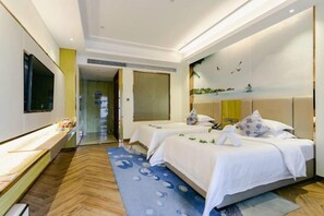 Habitación de hotel con dos camas, una televisión de pantalla plana, un escritorio y un ventanal grande.