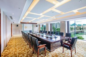 Un salón de conferencias con una mesa larga, sillas y una pantalla grande.
