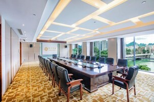 Un salón de conferencias con una mesa larga, sillas y una pantalla grande.