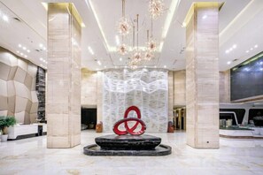 A lobby with a central sculpture, marble columns, and a modern chandelier. - Tongren Jinjiang Hotel (Tongren)