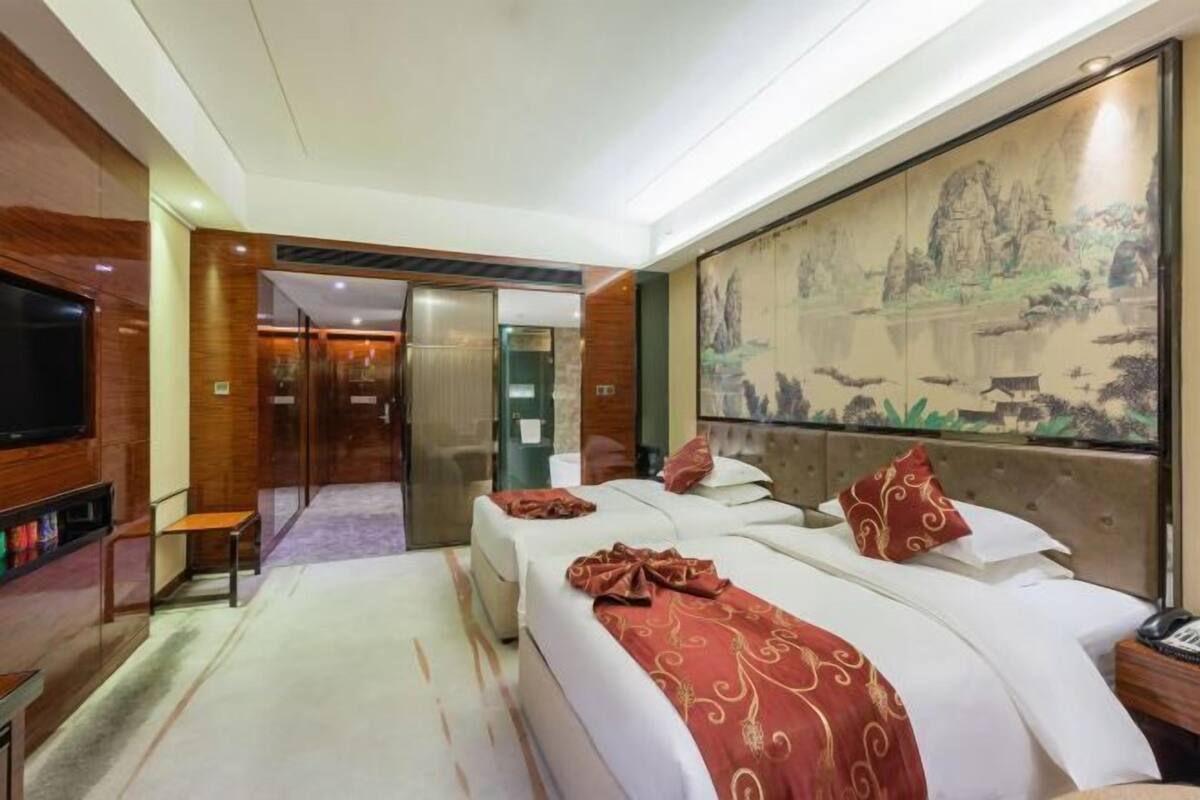Habitación de hotel con dos camas, un televisor, un cuadro y una pared de paneles de madera.