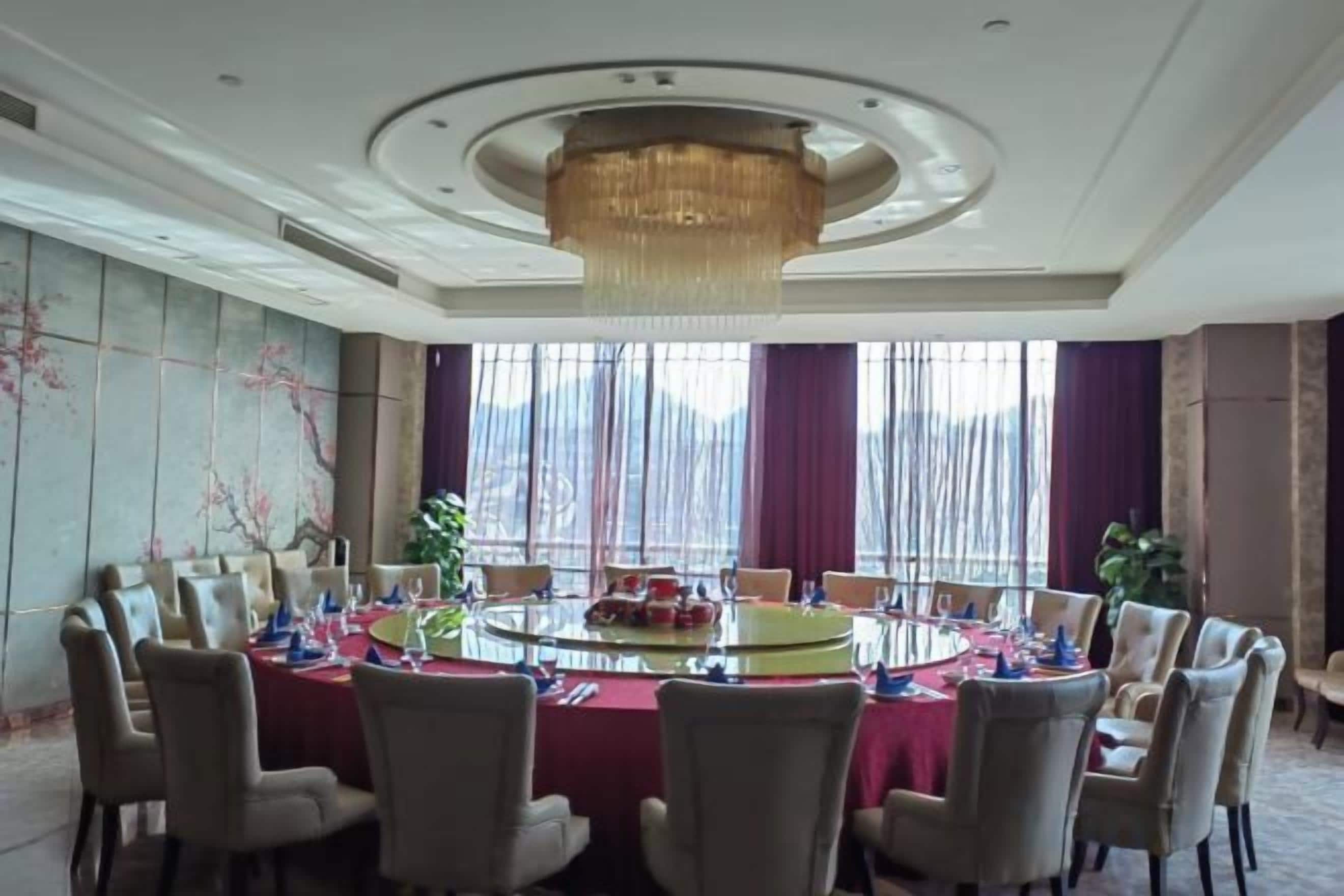 A conference room with a round table, chairs, and a chandelier.