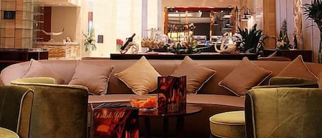 A modern hotel lobby with a sofa, chairs, a coffee table, and a decorative centerpiece.