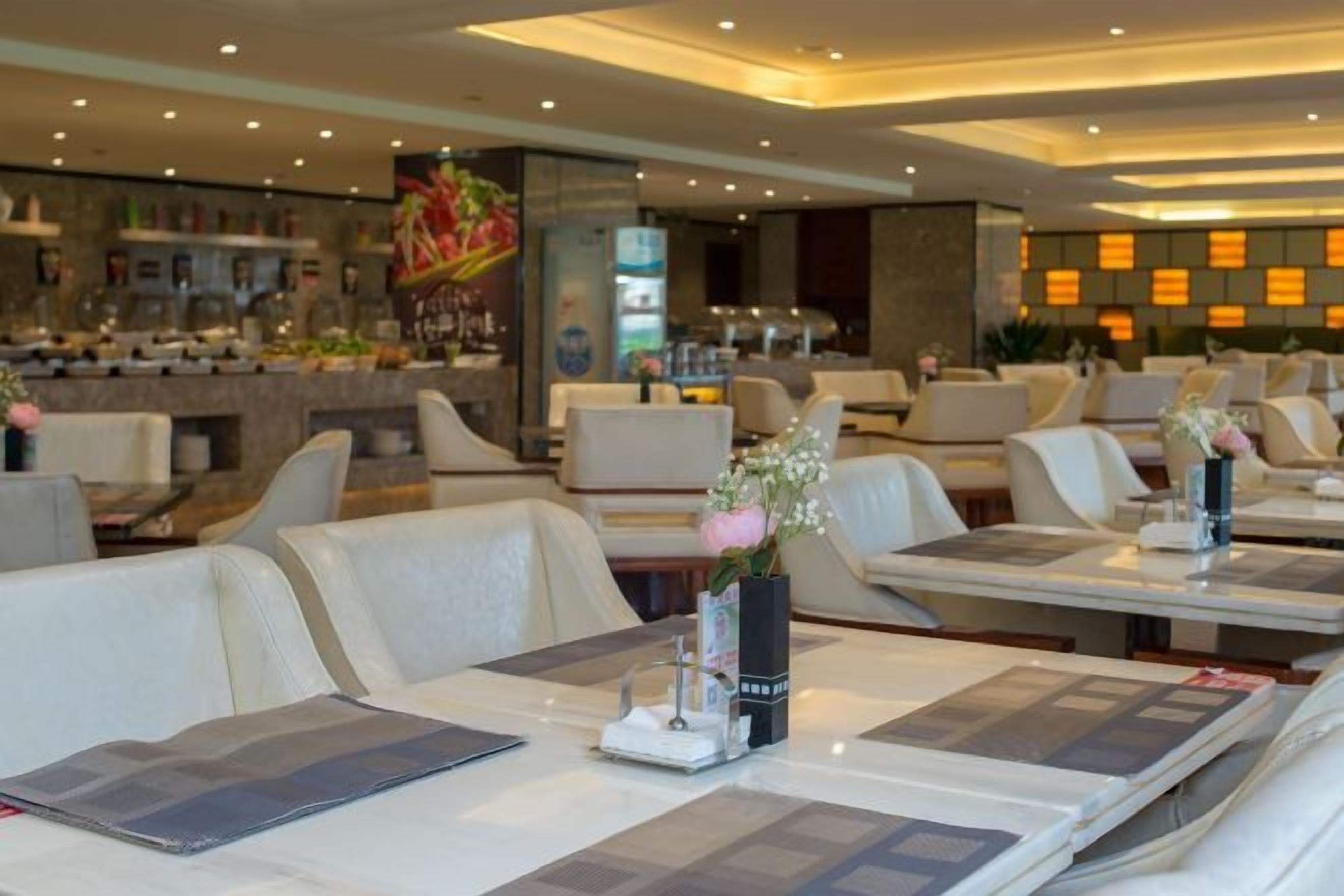 A restaurant with multiple dining tables, some with menus, and a bar area in the background.