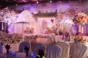 Un salón de banquetes con mesas redondas, sillas y centros de mesa florales.