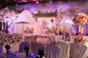 Un salón de banquetes con mesas redondas, sillas y centros de mesa florales.
