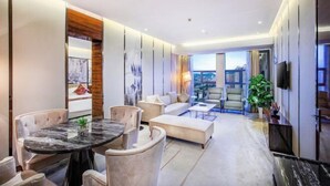 A modern hotel room with a dining area, sofa, and a large window offering a view. - Tongren Jinjiang Hotel (Tongren)