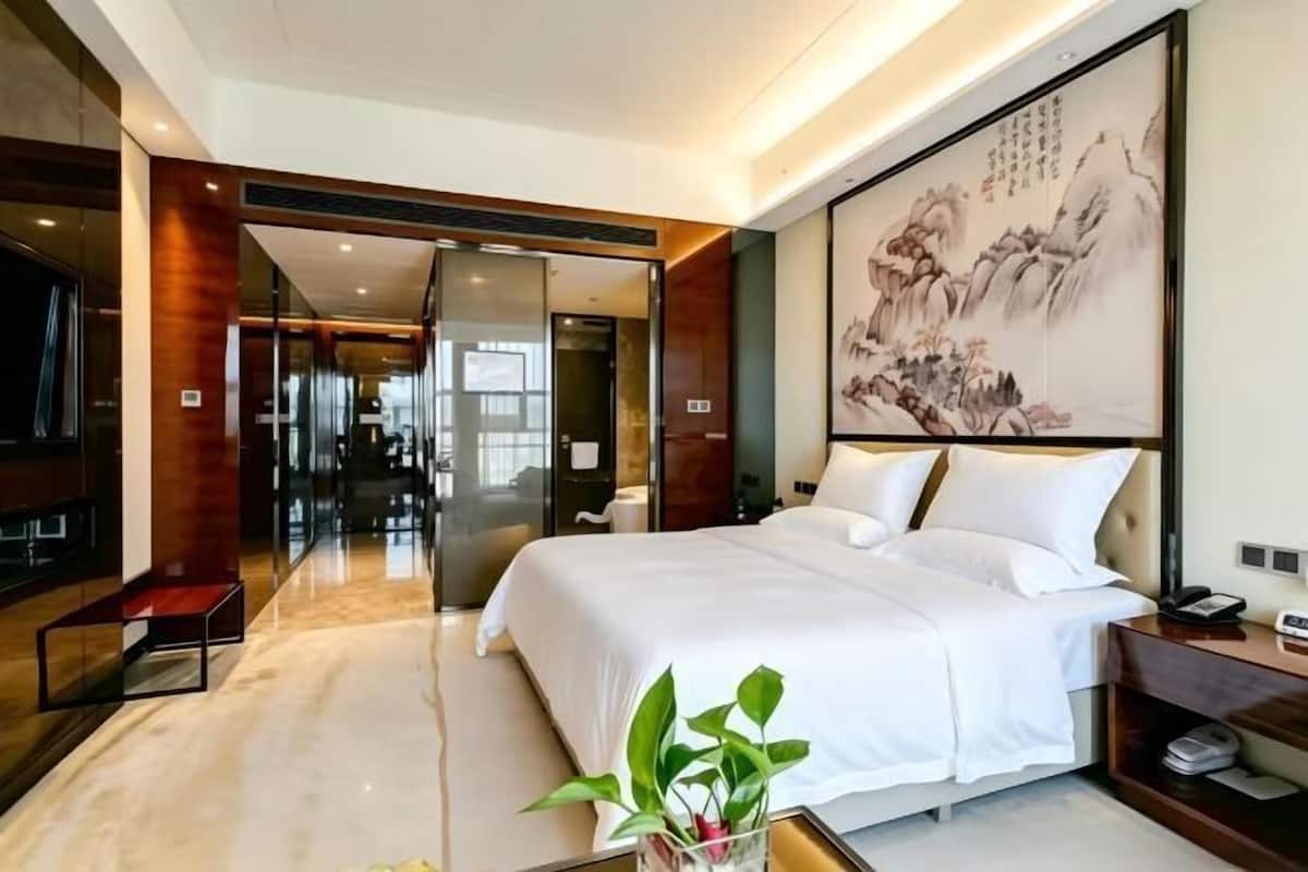 Una habitación de hotel moderna con una cama grande, una mesita de noche, un televisor y un cuadro en la pared.
