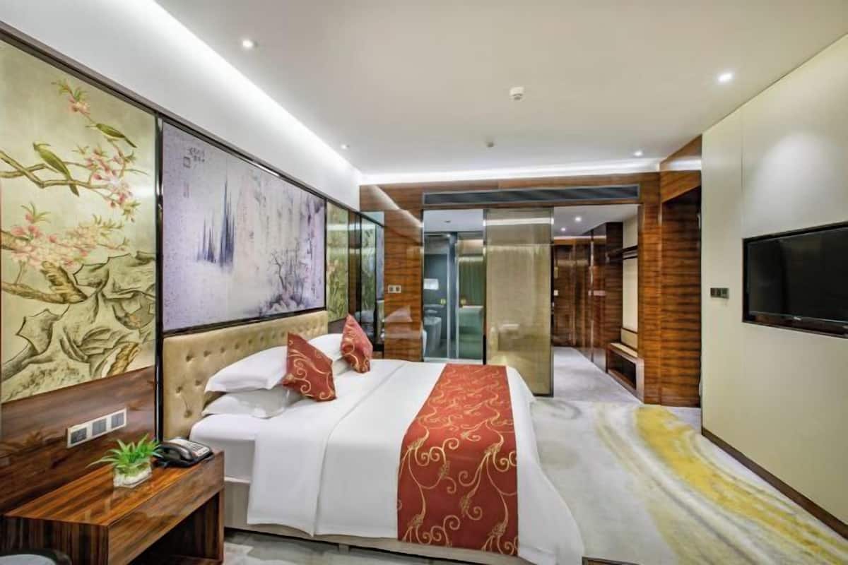 Una habitación de hotel moderna con una cama grande, un escritorio con teléfono y un televisor en la pared.