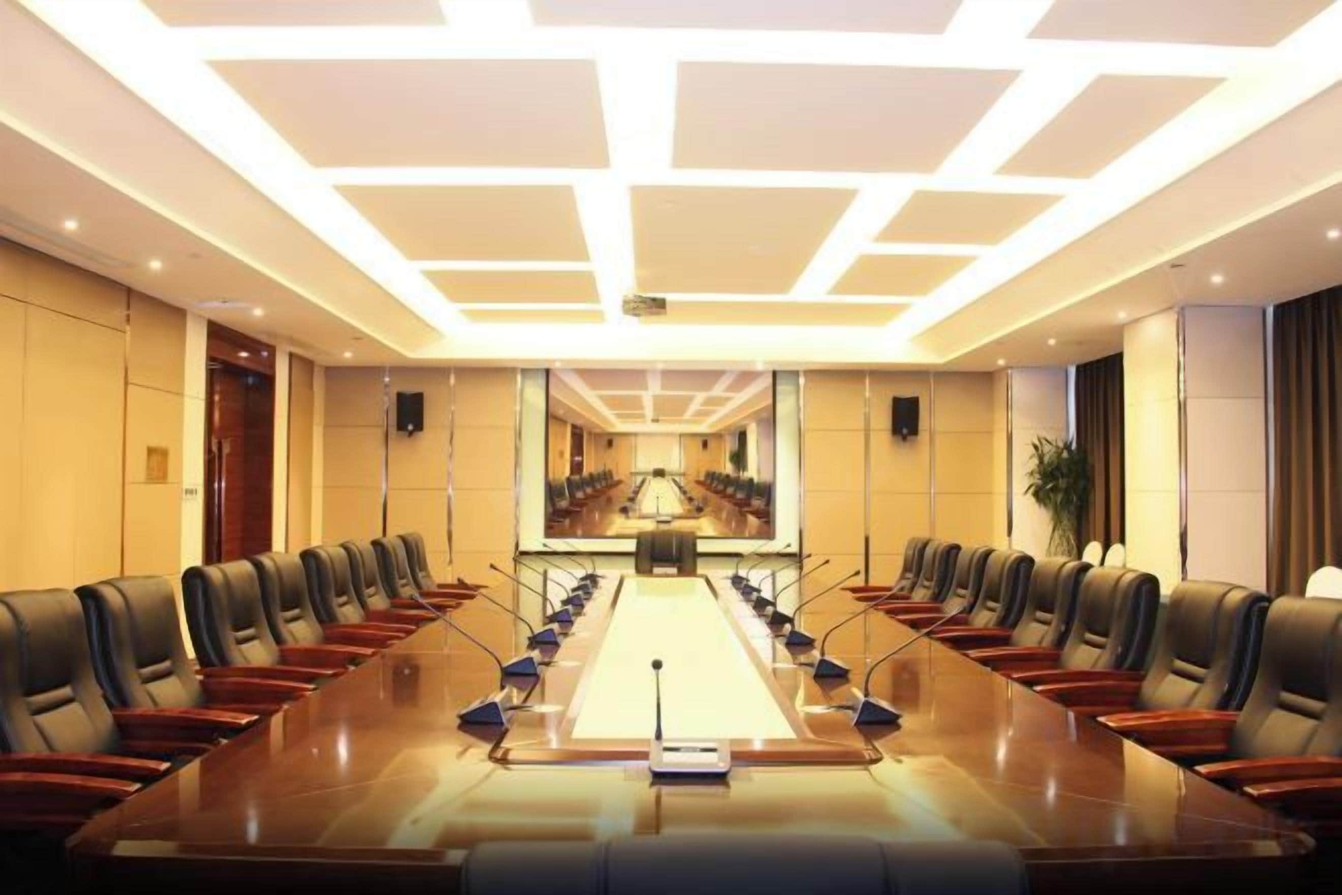 Un salón de conferencias con una larga mesa, sillas y una pantalla para proyector.