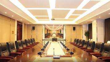 A conference room with a long table, chairs, and a projector screen.