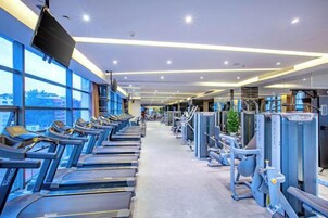 Un gimnasio con cintas de correr, máquinas de pesas y equipo de ejercicio.