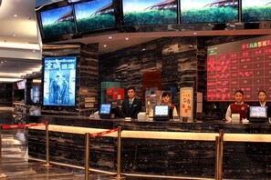 A hotel reception desk with multiple monitors, a marble counter, and a red information board. - Tongren Jinjiang Hotel (Tongren)