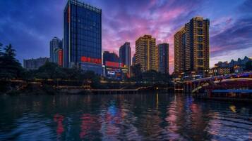 A cityscape with high-rise buildings and a river reflecting lights.