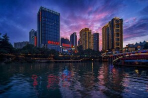 A cityscape with high-rise buildings and a river reflecting lights. - Tongren Jinjiang Hotel (Tongren)
