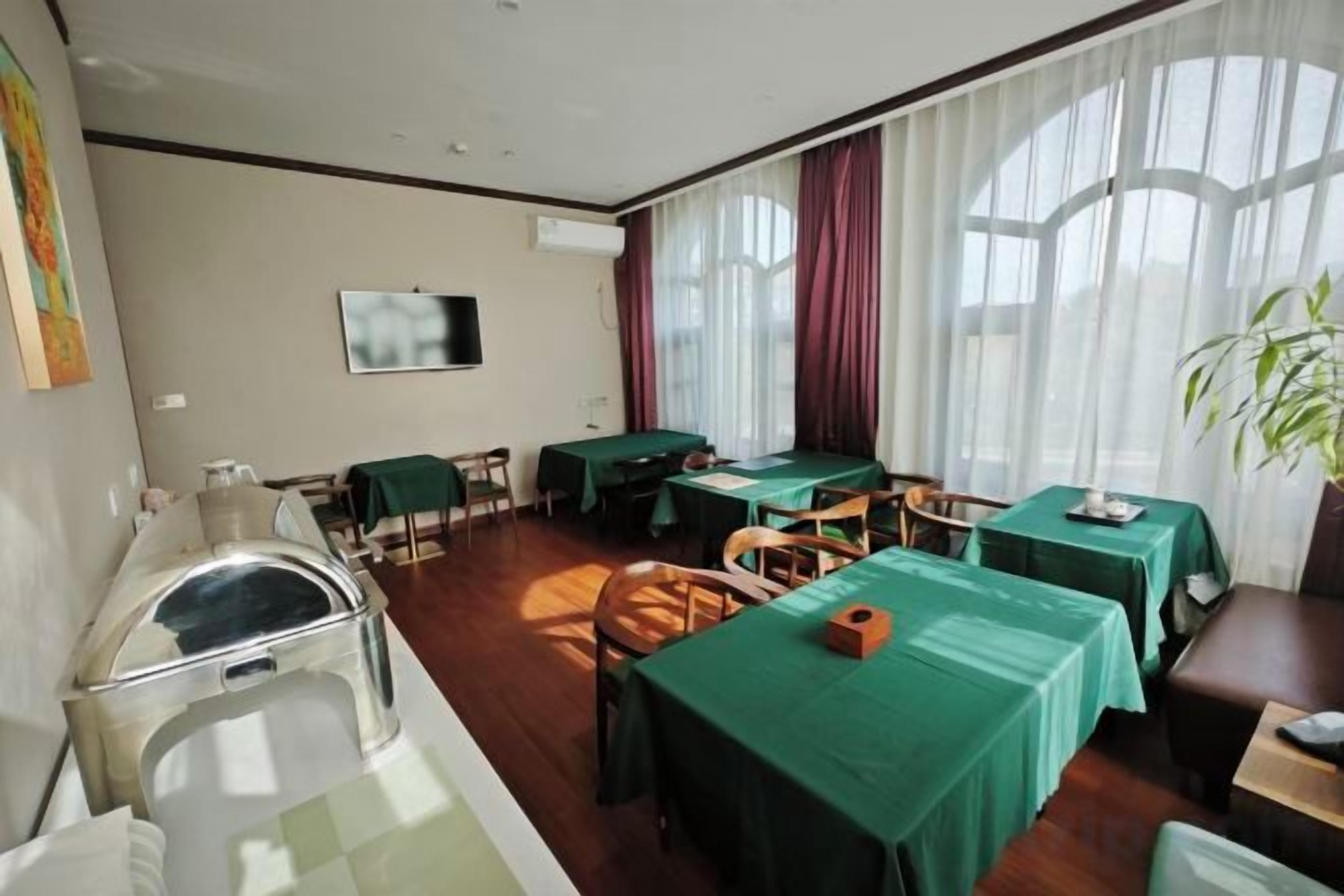 A hotel room with a dining area, a television, and a large window with curtains.
