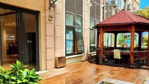 A wooden deck with a gazebo, potted plants, and a small water feature. - The XJ Hotel (Beijing)