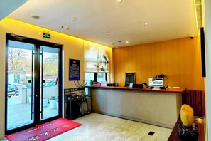 A reception area with a counter, a reception desk, and a door leading outside. - The XJ Hotel (Beijing)