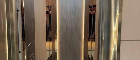 L’intérieur d’un ascenseur avec des parois métalliques et un sol réfléchissant.