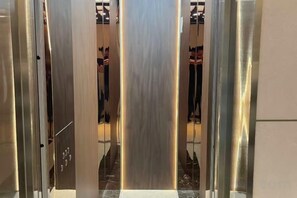 An elevator interior with metallic walls and a reflective floor. - The XJ Hotel (Beijing)