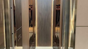 A modern elevator with metallic walls and a reflective surface. - The XJ Hotel (Beijing)