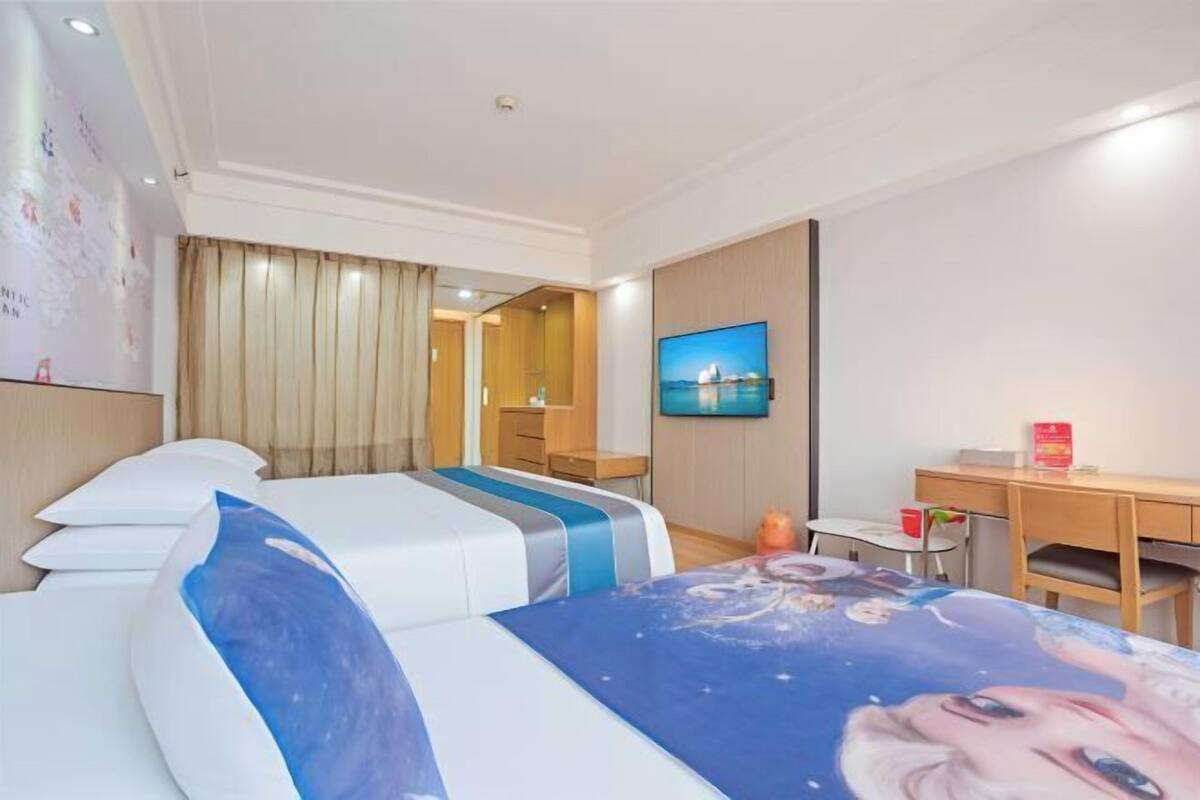 A hotel room with two beds, a desk, a chair, a TV, and a wall with a painting.