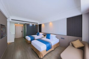 A hotel room with two beds, a sofa, and a large window. - Zhuhai City Center Hotel (Zhuhai)
