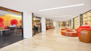 Un hall d’hôtel moderne avec un comptoir d’accueil, des espaces de détente et un grand vase.