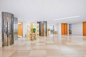 Un hall d’hôtel spacieux, doté d’un sol ciré, d’un comptoir d’accueil et d’un design moderne.