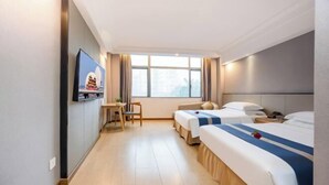 Une chambre d’hôtel avec deux lits, une télévision, un bureau et une fenêtre.