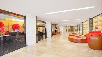 A modern hotel lobby with a polished floor, a reception desk, and a large decorative vase.