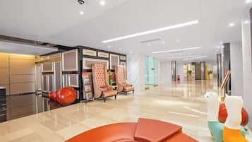 Un moderno vestíbulo de hotel con mostrador de recepción, zona de estar y un espejo grande.
