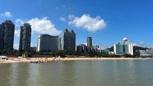 Un paisaje urbano costero con rascacielos, una playa y cielo despejado.