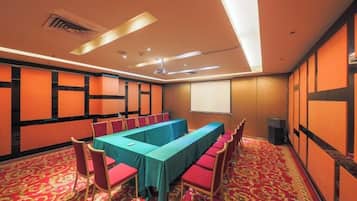 A conference room with a long table, chairs, and a projector screen.