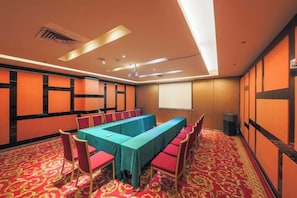 Une salle de conférence équipée d’une longue table, de chaises et d’un écran de projection.