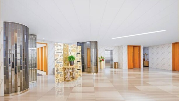 Un hall d’entrée spacieux, doté d’un sol à carreaux, d’une colonne décorative centrale et d’un espace de réception avec un mur en marbre.