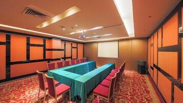 A conference room with a long table, red chairs, and a carpeted floor.
