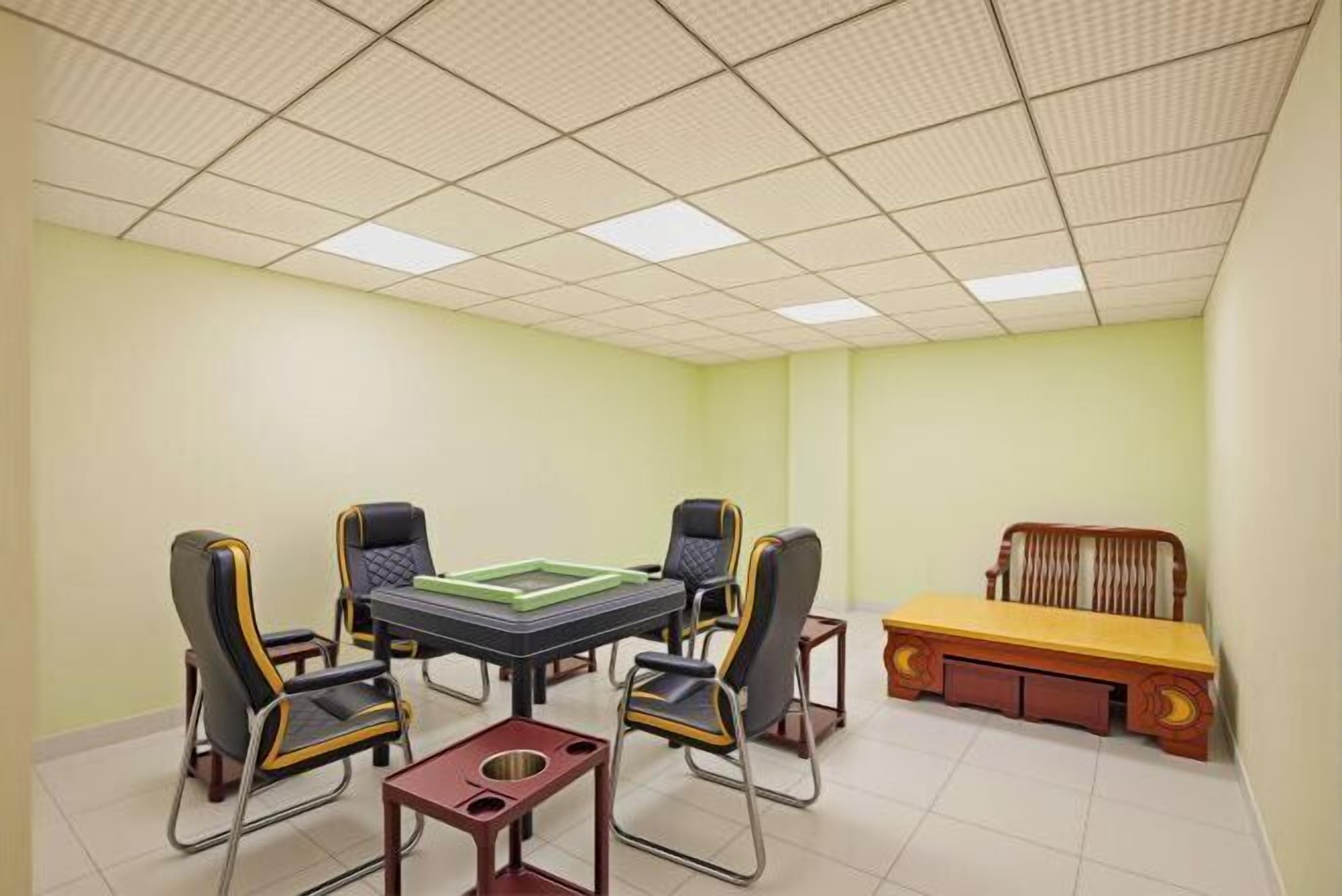 A conference room with a table and four chairs, a bench, and a tiled ceiling.