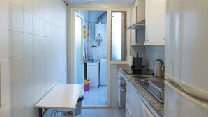 Una cocina compacta con armarios blancos, una encimera con hervidor y un lavamanos pequeño.